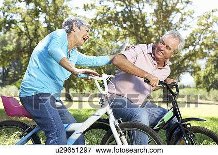 Senior couple playing on children's bikes View Large Photo Image Stock Photo - Senior couple playing on children's bikes. Fotosearch