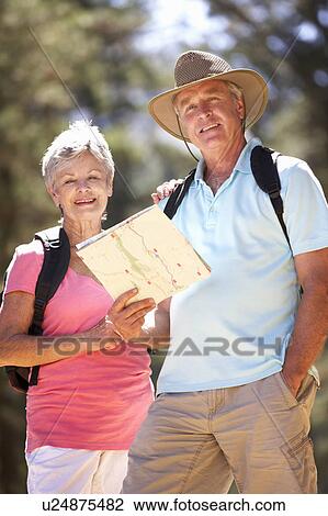 Stock Image - Senior couple reading map on country walk. Fotosearch