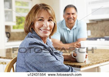 Picture - Senior couple relaxing in kitchen. Fotosearch