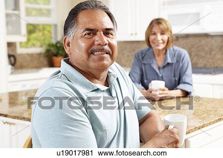 Stock Image - Senior couple relaxing in kitchen. Fotosearch