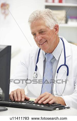 Stock Image - Senior doctor at desk. Fotosearch