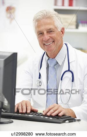 Stock Image - Senior doctor at desk. Fotosearch