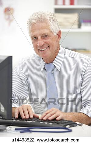Stock Image - Senior doctor at desk. Fotosearch