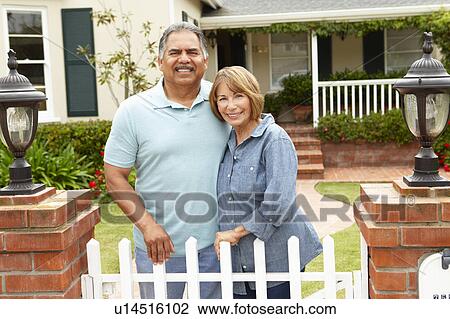 Stock Image - Senior Hispanic couple outside home. Fotosearch