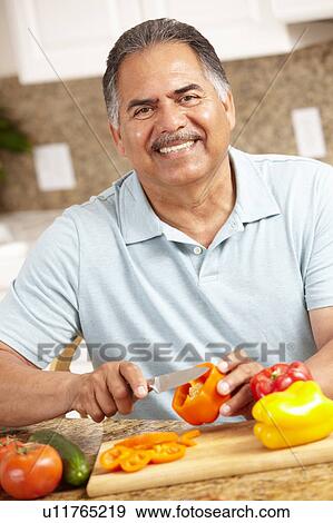 Stock Photo - Senior man chopping vegetables. Fotosearch