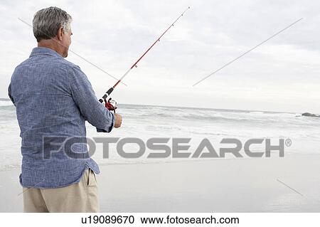 Stock Image - Senior man fishing in sea. Fotosearch