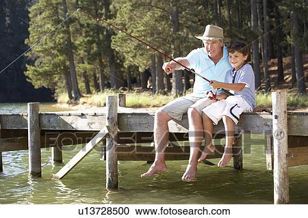 Stock Image - Senior man fishing with grandson. Fotosearch