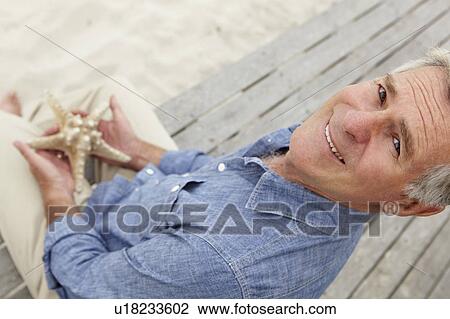 Stock Image - Senior man holding starfish. Fotosearch