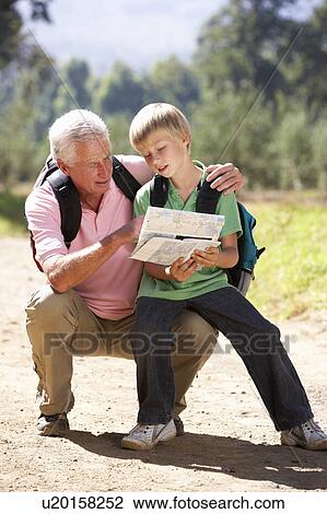 Stock Image - Senior man reading map with grandson on country walk. Fotosearch