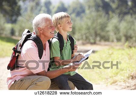 Stock Photo - Senior man reading map with grandson on country walk. Fotosearch