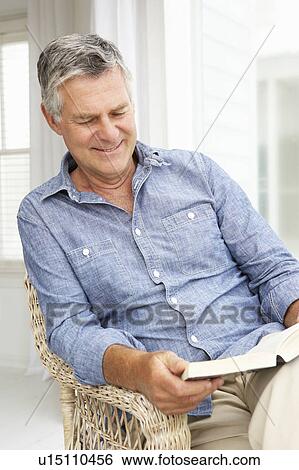 Stock Photograph - Senior man relaxing at home with a book. Fotosearch