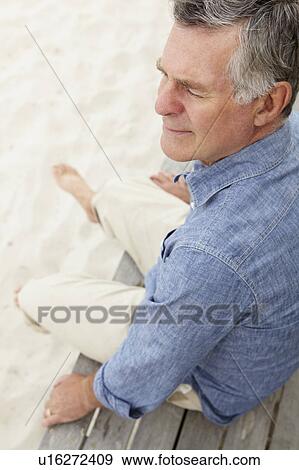 Senior man sitting by beach View Large Photo Image Stock Photo - Senior man sitting by beach. Fotosearch