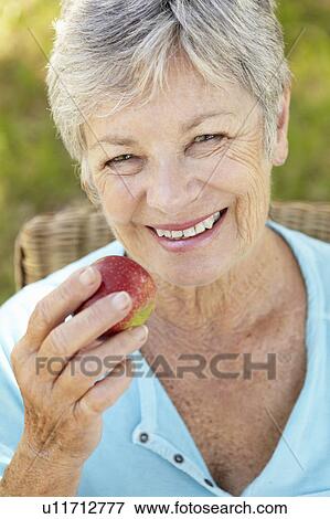 Stock Photo - Senior woman eating apple. Fotosearch