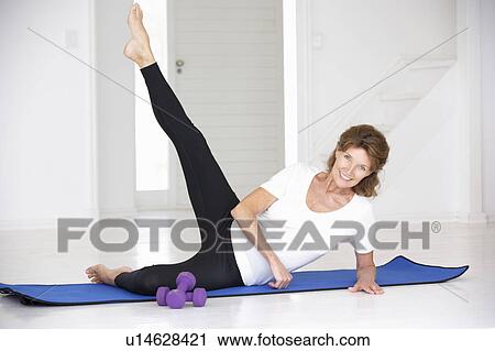 Stock Image - Senior woman exercising in home gym. Fotosearch