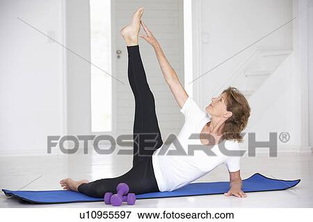 Stock Photo - Senior woman exercising in home gym. Fotosearch