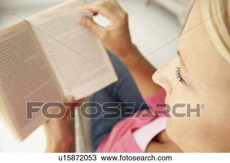 Stock Image - Senior woman reading book at home. Fotosearch