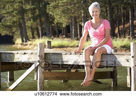 Senior woman sitting by lake View Large Photo Image Picture - Senior woman sitting by lake. Fotosearch