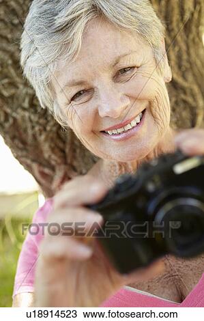 Stock Image - Senior woman with camera. Fotosearch