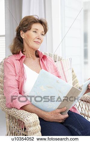 Stock Image - Senior woman with photo album. Fotosearch