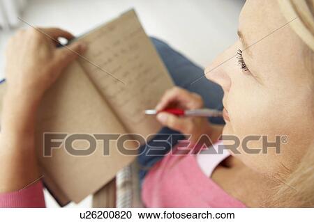 Stock Image - Senior woman writing in notebook. Fotosearch