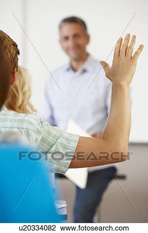 Stock Image - Student with hand up in class. Fotosearch
