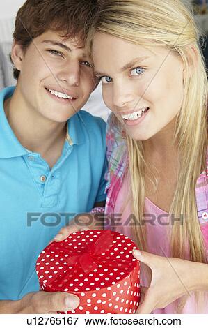 Teenage boy giving gift to girl View Large Photo Image Stock Photo - Teenage boy giving gift to girl. Fotosearch