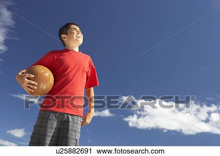 Stock Image - Teenage boy holding football. Fotosearch