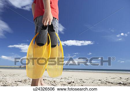 Stock Photograph - Teenage boy on beach with flippers. Fotosearch