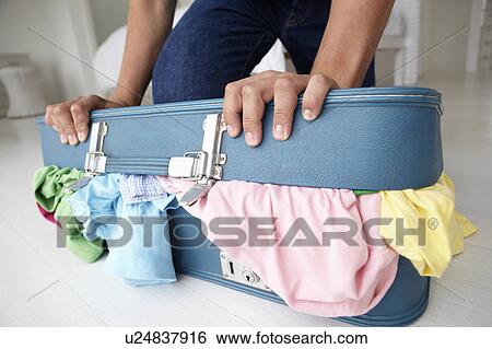 Teenage boy struggling to close suitcase View Large Photo Image Stock Photograph - Teenage boy struggling to close suitcase. Fotosearch