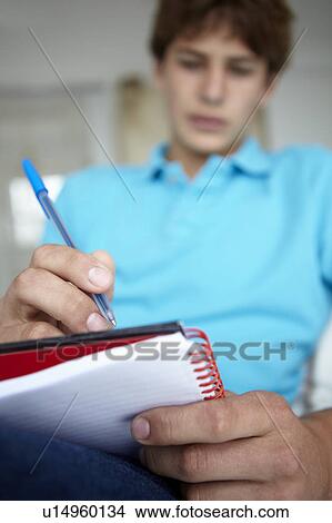 Picture - Teenage boy writing in notebook. Fotosearch
