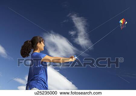 Stock Image - Teenage girl flying a kite. Fotosearch