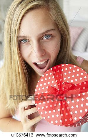 Stock Image - Teenage girl holding gift box. Fotosearch