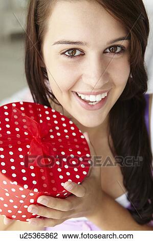 Stock Image - Teenage girl holding gift box. Fotosearch
