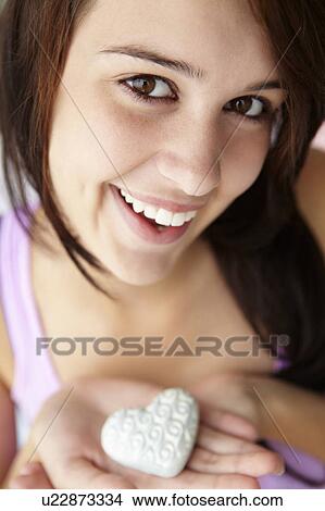 Picture - Teenage girl holding silver heart. Fotosearch