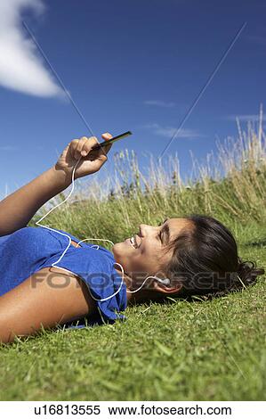 Teenage girl lying on grass with mp3 player View Large Photo Image Stock Photography - Teenage girl lying on grass with mp3 player. Fotosearch