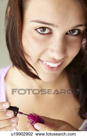 Stock Image - Teenage girl painting nails. Fotosearch