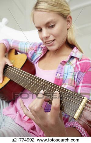 Stock Image - Teenage girl playing acoustic guitar. Fotosearch