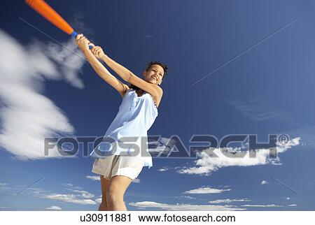 Stock Image - Teenage girl playing baseball on beach. Fotosearch