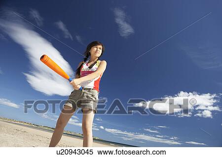 Stock Photography - Teenage girl playing baseball on beach. Fotosearch