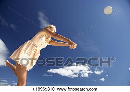 Stock Image - Teenage girl playing beach volleyball. Fotosearch