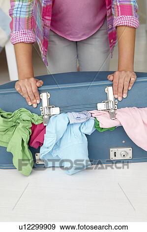 Teenage girl struggling to close suitcase View Large Photo Image Stock Photo - Teenage girl struggling to close suitcase. Fotosearch