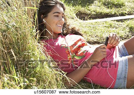 Stock Photo - Teenage girl using mp3 player outdoors. Fotosearch