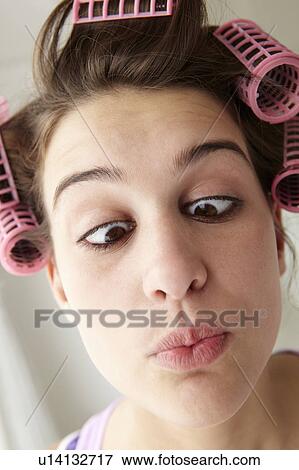 Stock Photo - Teenage girl with hair in curlers pulling a face. Fotosearch