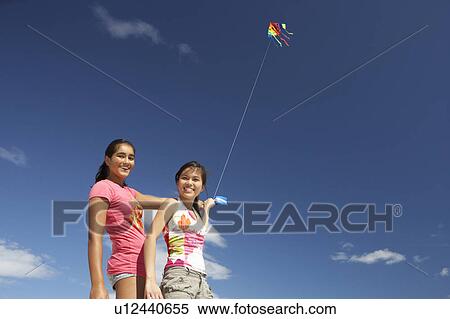 Teenage girls flying a kite View Large Photo Image Stock Photography - Teenage girls flying a kite. Fotosearch