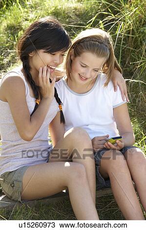 Teenage girls using phone outdoors View Large Photo Image Stock Image - Teenage girls using phone outdoors. Fotosearch