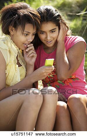 Teenage girls using phone outdoors View Large Photo Image Stock Photo - Teenage girls using phone outdoors. Fotosearch