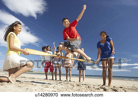 Stock Image - Teenagers having fun on beach. Fotosearch
