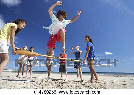 Stock Photograph - Teenagers having fun on beach. Fotosearch