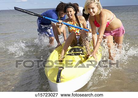 Teenagers in sea with canoe View Large Photo Image Stock Photo - Teenagers in sea with canoe. Fotosearch