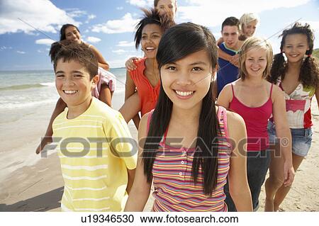 Stock Image - Teenagers walking on beach. Fotosearch